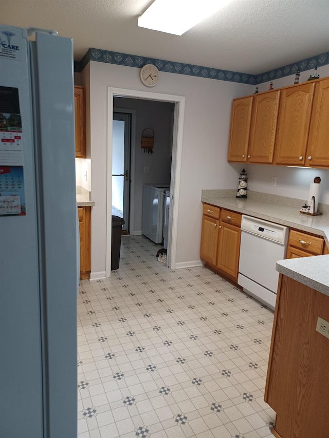 3144 Amsterdam Dr, Clio, MI 48420 - kitchen with white appliances, washer / dryer, light floors, light countertops, and brown cabinetry