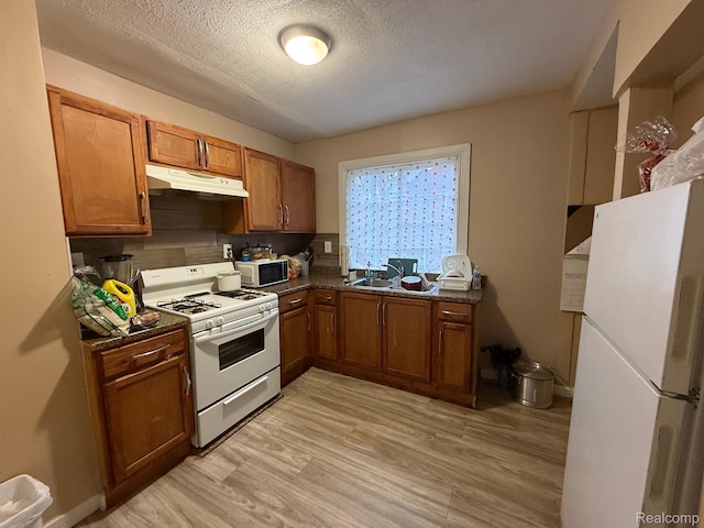 9208 Ward St, Detroit, MI 48228 - kitchen featuring white appliances, under cabinet range hood, dark countertops, brown cabinetry, and a textured ceiling