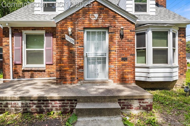 11108 Craft St, Detroit, MI 48224 - property entrance with a shingled roof, a chimney, and brick siding