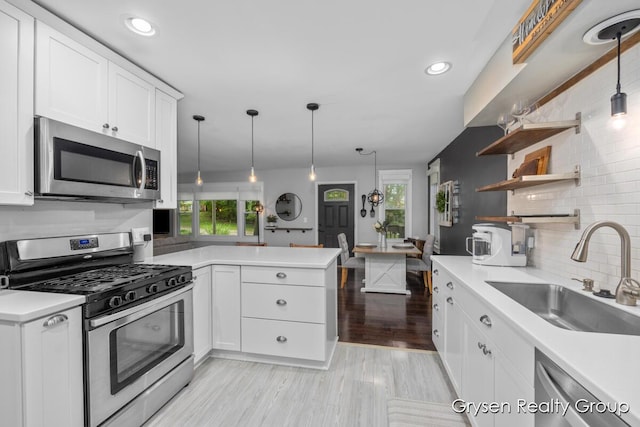 431 Homecrest Ave, Kalamazoo, MI 49001 - kitchen featuring appliances with stainless steel finishes, decorative backsplash, a peninsula, white cabinetry, and light countertops