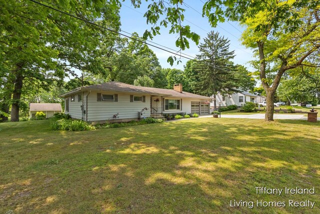 11737 W Carson City Rd, Greenville, MI 48838 - view of front of house with a chimney, a front lawn, and an attached garage