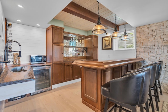 11786 E Sauk Trl, Jerome, MI 49249 - indoor bar with light wood-type flooring, stainless steel microwave, wine cooler, decorative light fixtures, and a wooden ceiling with exposed beams
