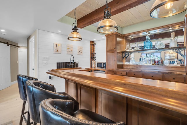 11786 E Sauk Trl, Jerome, MI 49249 - indoor bar featuring a barn door, stainless steel microwave, light wood-style flooring, decorative light fixtures, and beam ceiling