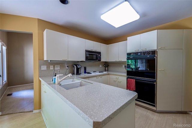 6760 Oyster Cv, West Bloomfield, MI 48323 - kitchen featuring black appliances, a peninsula, light wood-style floors, and decorative backsplash