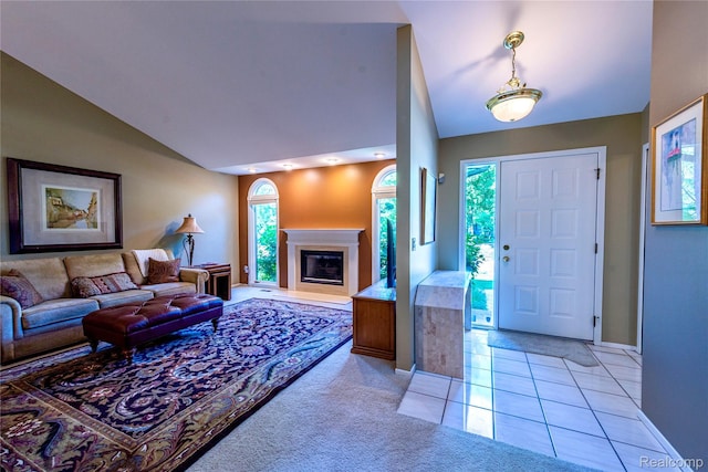 6760 Oyster Cv, West Bloomfield, MI 48323 - living room featuring vaulted ceiling, a glass covered fireplace, light tile patterned floors, and light carpet