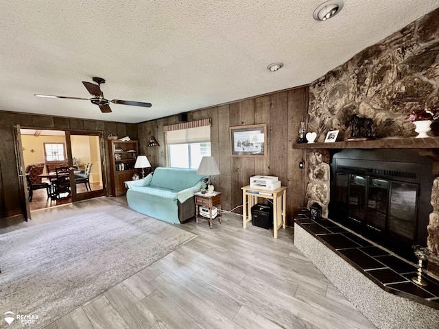 449 Noric Dr, Roscommon, MI 48653 - living room featuring a textured ceiling, plenty of natural light, wood walls, ceiling fan, and a fireplace