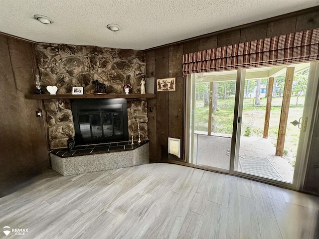 449 Noric Dr, Roscommon, MI 48653 - unfurnished living room with wood finished floors, a fireplace, a textured ceiling, and wood walls