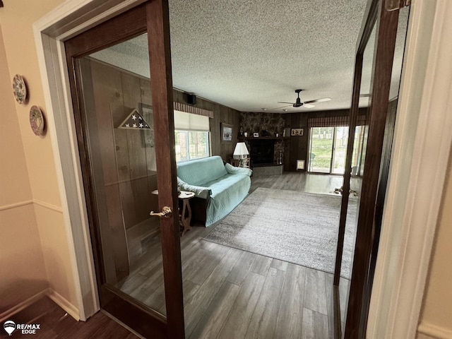449 Noric Dr, Roscommon, MI 48653 - bathroom featuring a ceiling fan, wood finished floors, a textured ceiling, wooden walls, and a stone fireplace