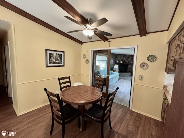 449 Noric Dr, Roscommon, MI 48653 - dining room featuring a large fireplace, ceiling fan, dark wood-type flooring, and beamed ceiling