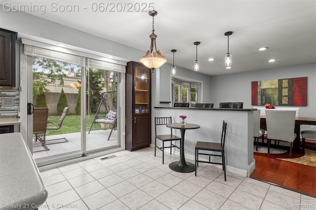 2138 Metzner Rd, Commerce Twp, MI 48390 - kitchen with light tile patterned flooring, recessed lighting, hanging light fixtures, dark brown cabinetry, and a breakfast bar area