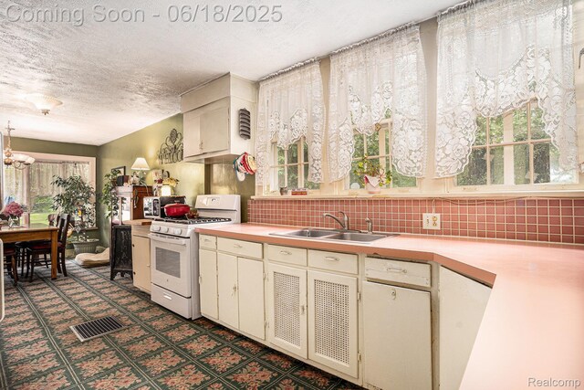 44988 52nd St, Lawrence, MI 49064 - kitchen featuring white range with gas stovetop, light countertops, healthy amount of natural light, a textured ceiling, and tasteful backsplash