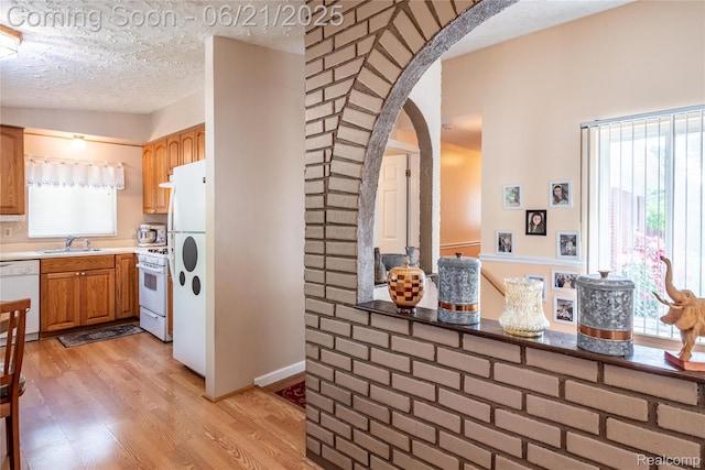 8311 Gulley St, Taylor, MI 48180 - kitchen featuring white appliances, arched walkways, light wood-style floors, light countertops, and brown cabinetry