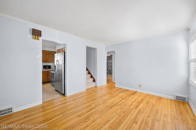 22902 Olmstead St, Dearborn, MI 48124 - empty room featuring crown molding, arched walkways, light wood-type flooring, and stairway