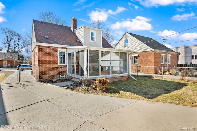 22902 Olmstead St, Dearborn, MI 48124 - back of property with a sunroom, a gate, brick siding, a chimney, and concrete driveway