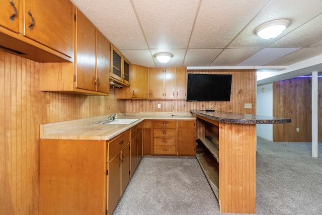 531 Gettysburg Dr, Niles, MI 49120 - kitchen featuring light colored carpet, a peninsula, wood walls, brown cabinets, and a paneled ceiling