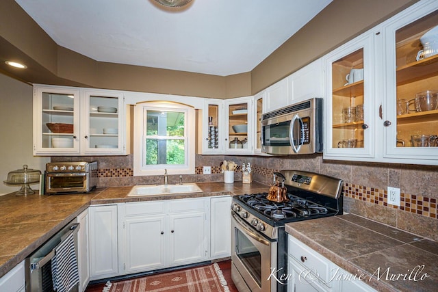 6072 Del Cano Dr SE, Grand Rapids, MI 49546 - kitchen with appliances with stainless steel finishes, white cabinets, and tasteful backsplash