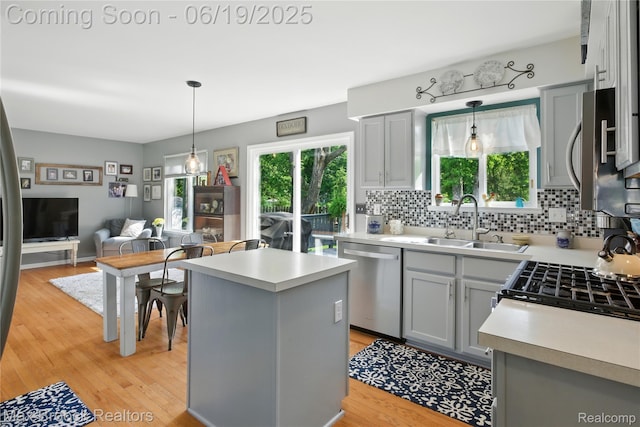 7950 Sandmar Ln, Davisburg, MI 48350 - kitchen featuring appliances with stainless steel finishes, open floor plan, a kitchen island, tasteful backsplash, and light countertops