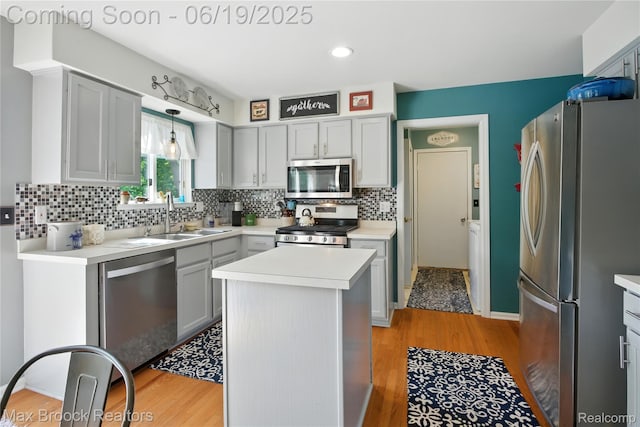 7950 Sandmar Ln, Davisburg, MI 48350 - kitchen with stainless steel appliances, light wood finished floors, tasteful backsplash, light countertops, and a center island