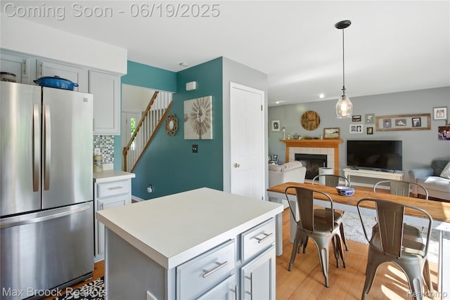 7950 Sandmar Ln, Davisburg, MI 48350 - kitchen with freestanding refrigerator, light wood-style floors, light countertops, a tile fireplace, and backsplash