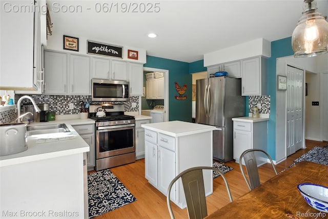 7950 Sandmar Ln, Davisburg, MI 48350 - kitchen with stainless steel appliances, washing machine and clothes dryer, tasteful backsplash, light countertops, and light wood finished floors