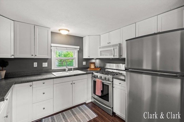 1873 Veronica St SE, Lowell, MI 49331 - kitchen with appliances with stainless steel finishes, dark countertops, white cabinets, and dark wood-style flooring