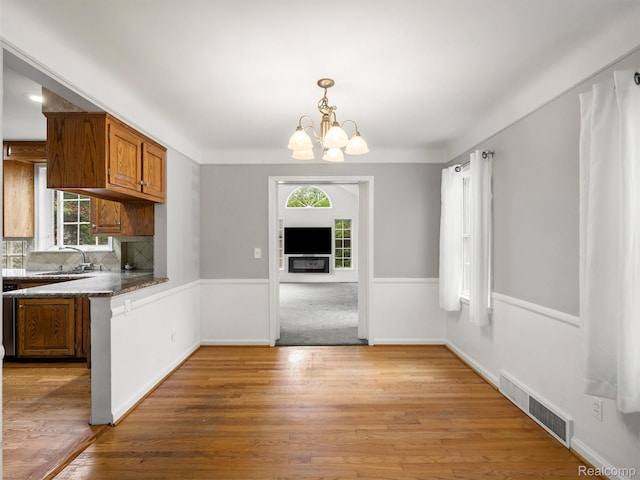1930 Kenmore Dr, Grosse Pointe Woods, MI 48236 - kitchen with a chandelier, brown cabinets, tasteful backsplash, light wood-type flooring, and hanging light fixtures