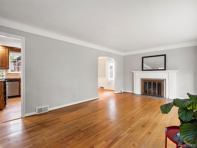 1930 Kenmore Dr, Grosse Pointe Woods, MI 48236 - unfurnished living room with light wood-style floors, arched walkways, and a fireplace with flush hearth