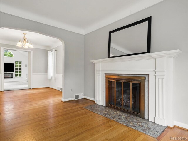 1930 Kenmore Dr, Grosse Pointe Woods, MI 48236 - unfurnished living room featuring wood finished floors, a fireplace with flush hearth, and arched walkways