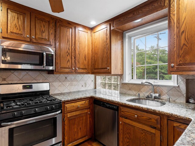 1930 Kenmore Dr, Grosse Pointe Woods, MI 48236 - kitchen with stainless steel appliances, light stone countertops, tasteful backsplash, brown cabinets, and ceiling fan