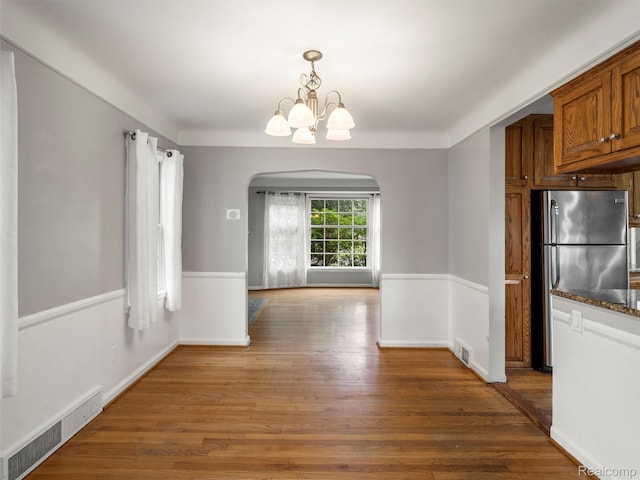 1930 Kenmore Dr, Grosse Pointe Woods, MI 48236 - unfurnished dining area with arched walkways, light wood-type flooring, and a chandelier