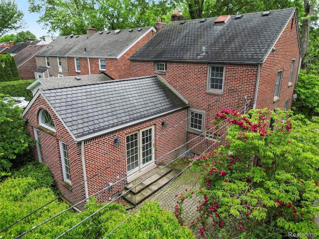 1930 Kenmore Dr, Grosse Pointe Woods, MI 48236 - rear view of property with brick siding, french doors, a chimney, and a high end roof