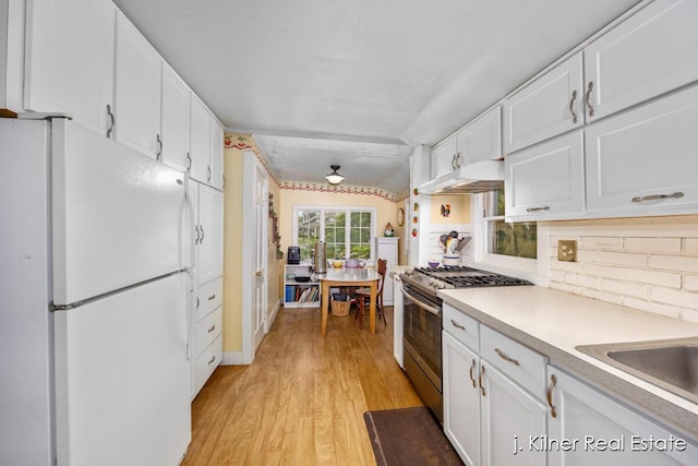 7115 Bronson St SE, Ada, MI 49301 - kitchen with freestanding refrigerator, stainless steel range with gas stovetop, under cabinet range hood, and white cabinetry