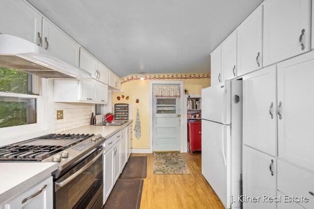 7115 Bronson St SE, Ada, MI 49301 - kitchen with gas range, freestanding refrigerator, light wood-type flooring, white cabinets, and light countertops