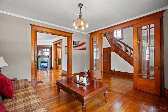 203 S Main St, Onsted, MI 49265 - living area featuring wood-type flooring, a chandelier, stairs, a fireplace with flush hearth, and crown molding