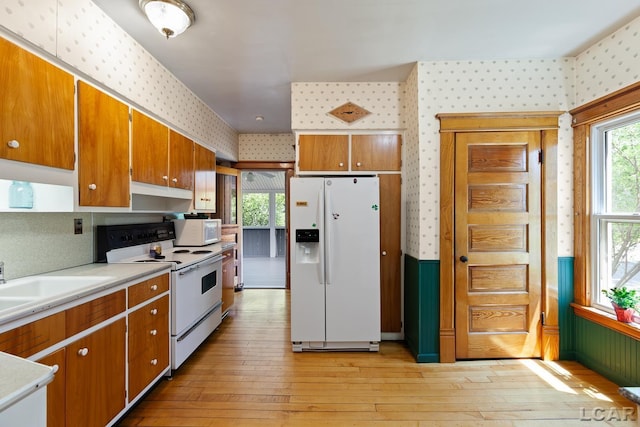 203 S Main St, Onsted, MI 49265 - kitchen with white appliances, wallpapered walls, brown cabinets, light wood-style flooring, and light countertops