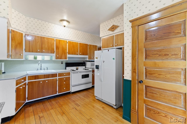 203 S Main St, Onsted, MI 49265 - kitchen with wallpapered walls, white appliances, light countertops, light wood-type flooring, and brown cabinets