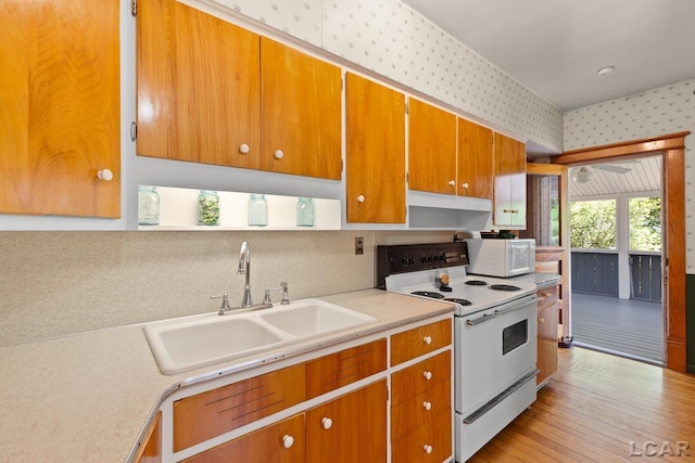 203 S Main St, Onsted, MI 49265 - kitchen featuring white appliances, wallpapered walls, light countertops, brown cabinetry, and light wood-style flooring