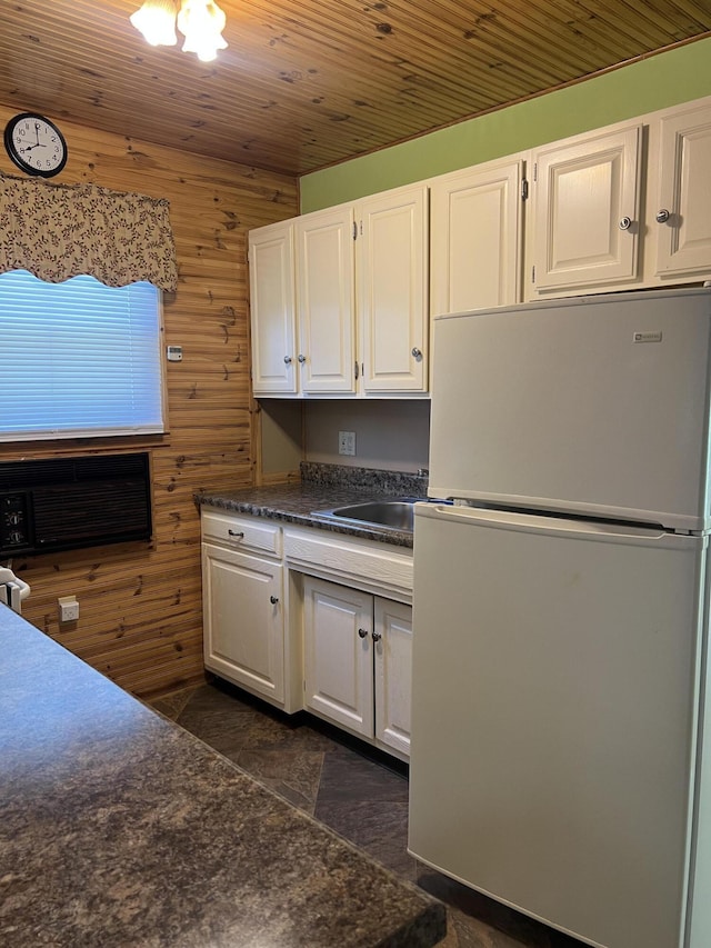 7428 Ansley Ln, Hillsdale, MI 49242 - kitchen with freestanding refrigerator, white cabinets, wooden walls, dark countertops, and dark stone finish flooring