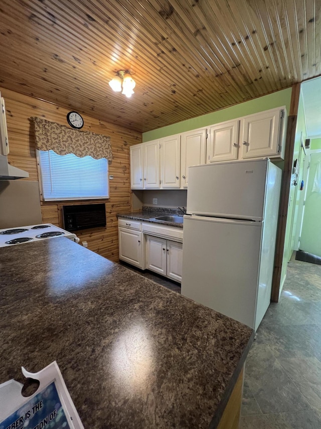 7428 Ansley Ln, Hillsdale, MI 49242 - kitchen featuring white appliances, dark countertops, white cabinetry, wooden walls, and exhaust hood