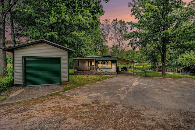 8933 E M 20, Hesperia, MI 49421 - view of front of property featuring driveway, an outbuilding, a carport, a detached garage, and a porch