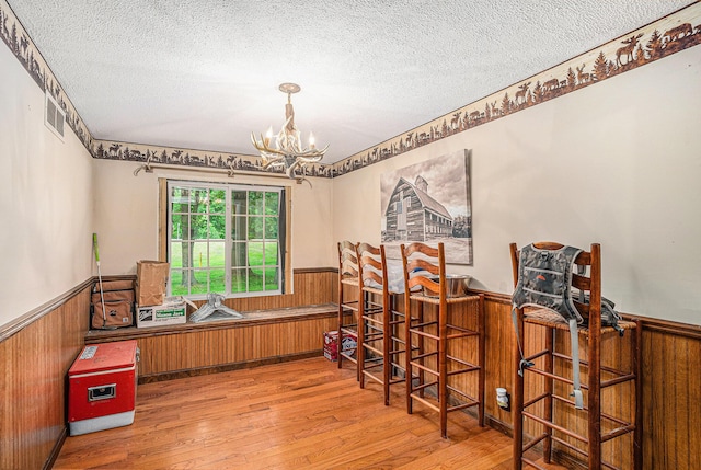 8933 E M 20, Hesperia, MI 49421 - dining room featuring a wainscoted wall, a textured ceiling, wood finished floors, a chandelier, and wooden walls