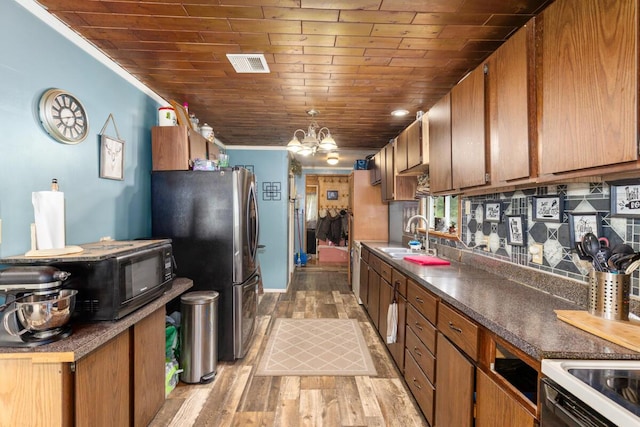 11681 Heron Dr, Lakeview, MI 48850 - kitchen with freestanding refrigerator, dark countertops, light wood finished floors, wooden ceiling, and a chandelier