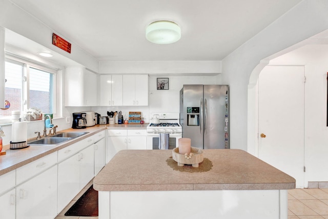 29206 Guy St, Southfield, MI 48076 - kitchen featuring stainless steel fridge, white gas stove, a kitchen island, white cabinets, and light tile patterned floors