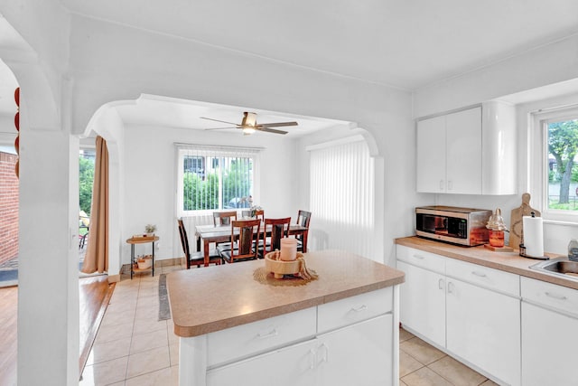 29206 Guy St, Southfield, MI 48076 - kitchen featuring stainless steel microwave, light tile patterned floors, arched walkways, ceiling fan, and a kitchen island