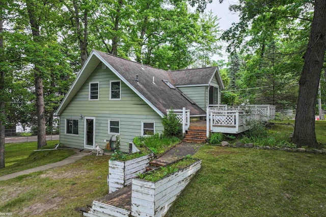 7199 Switzer Dr, Linden, MI 48451 - view of front of home with a shingled roof, a front lawn, a deck, and a garden