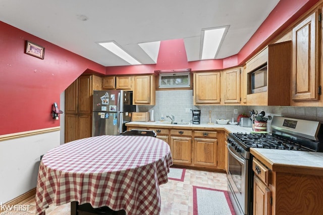 7199 Switzer Dr, Linden, MI 48451 - kitchen featuring stainless steel appliances, tile countertops, decorative backsplash, and brown cabinets