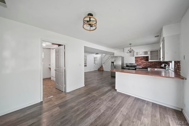 306 S Washington St, Manchester, MI 48158 - kitchen featuring appliances with stainless steel finishes, dark wood-type flooring, a peninsula, glass insert cabinets, and decorative backsplash