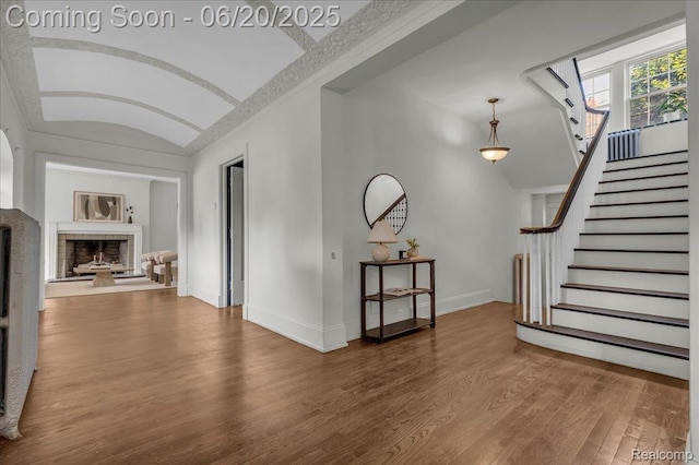 1710 Seminole St, Detroit, MI 48214 - unfurnished living room featuring wood finished floors, stairs, vaulted ceiling, and a fireplace with raised hearth