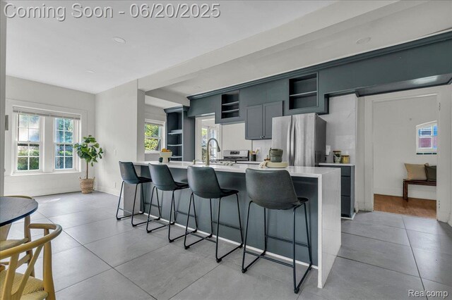1710 Seminole St, Detroit, MI 48214 - kitchen featuring freestanding refrigerator, open shelves, a breakfast bar area, light tile patterned floors, and light countertops