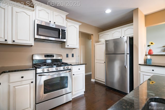 4096 Villager Dr, Lake Orion, MI 48359 - kitchen featuring appliances with stainless steel finishes, dark stone counters, white cabinetry, dark wood-style flooring, and recessed lighting